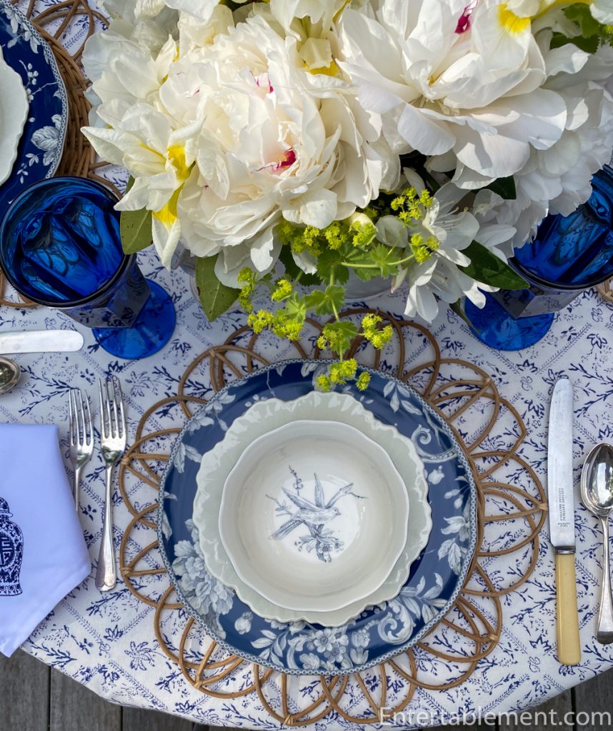 Close-up of Adelaide in Navy bowl by 222 Fifth with intricate white peony design on navy glaze, atop a cream scalloped salad plate.