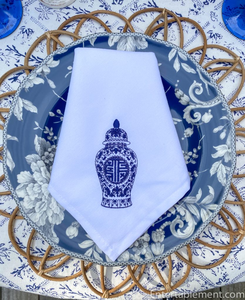 White napkin with navy embroidered chinoiserie ginger jar design placed over Adelaide navy dinner plate.