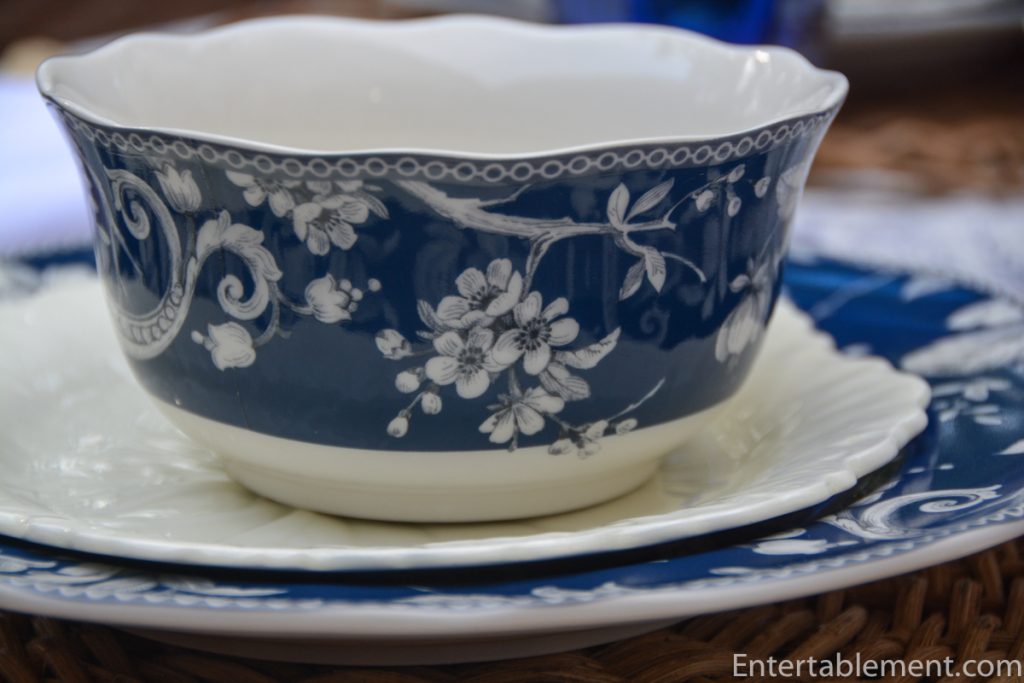 Close-up of Adelaide in Navy bowl by 222 Fifth with intricate white peony design on navy glaze, atop a cream scalloped Vintage Wedgwood salad plate.