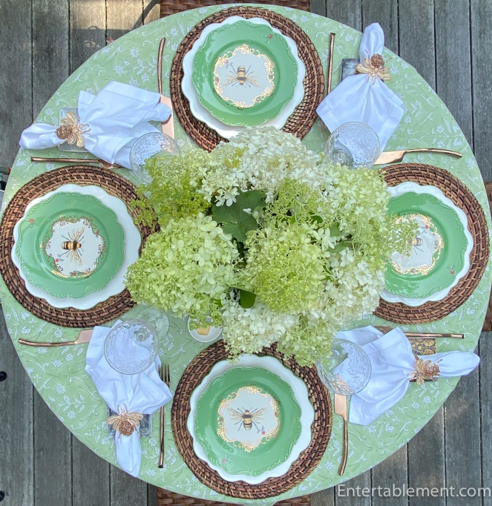 Overhead view of a late summer garden tablescape with Anthropologie Nature Studies Bee plates, Limelight hydrangeas, woven chargers and bee napkin rings.