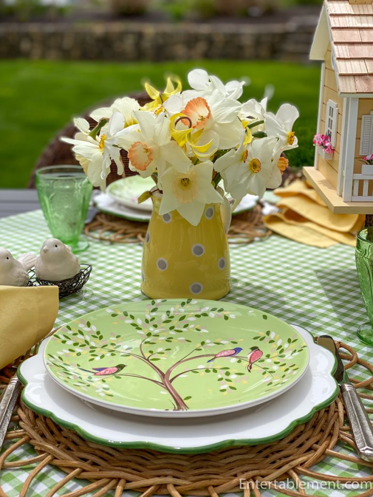 White and yellow daffodils in a pitcher with small decorative birds in a nest on a spring table