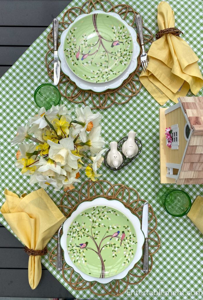 Green plate with bird design on woven placemat, paired with yellow napkin and green glass