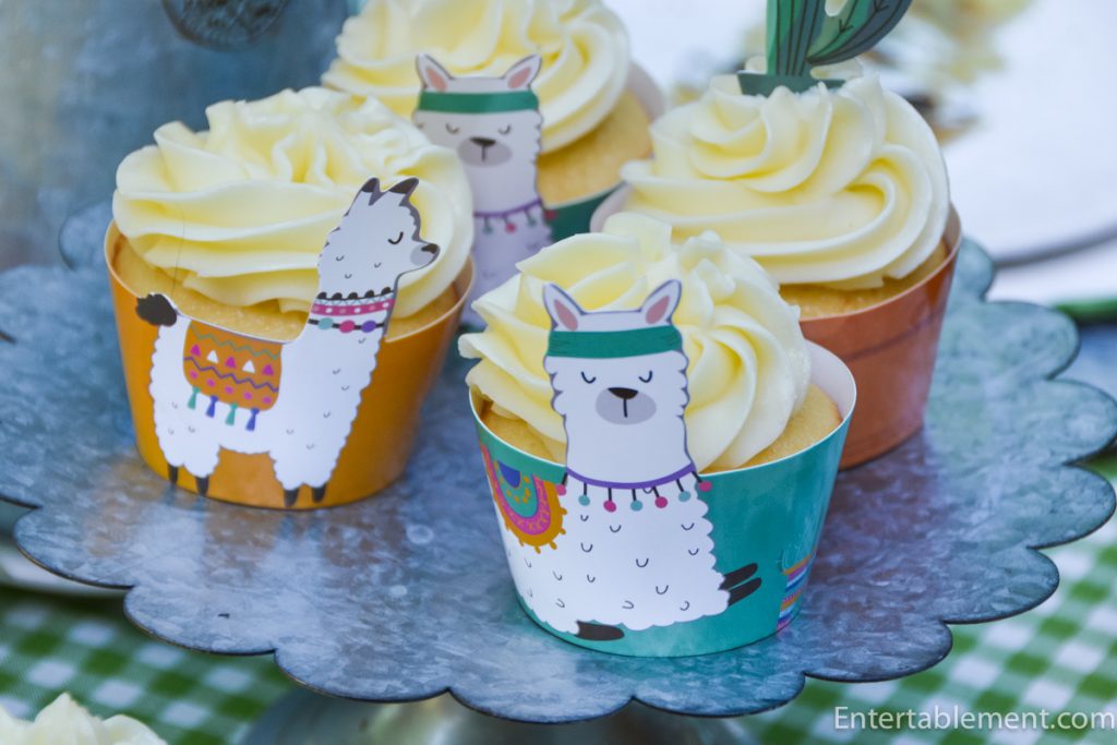Vanilla cupcakes with raspberry filling and piped lime Swiss Meringue Buttercream in colourful llama cupcake wrappers.