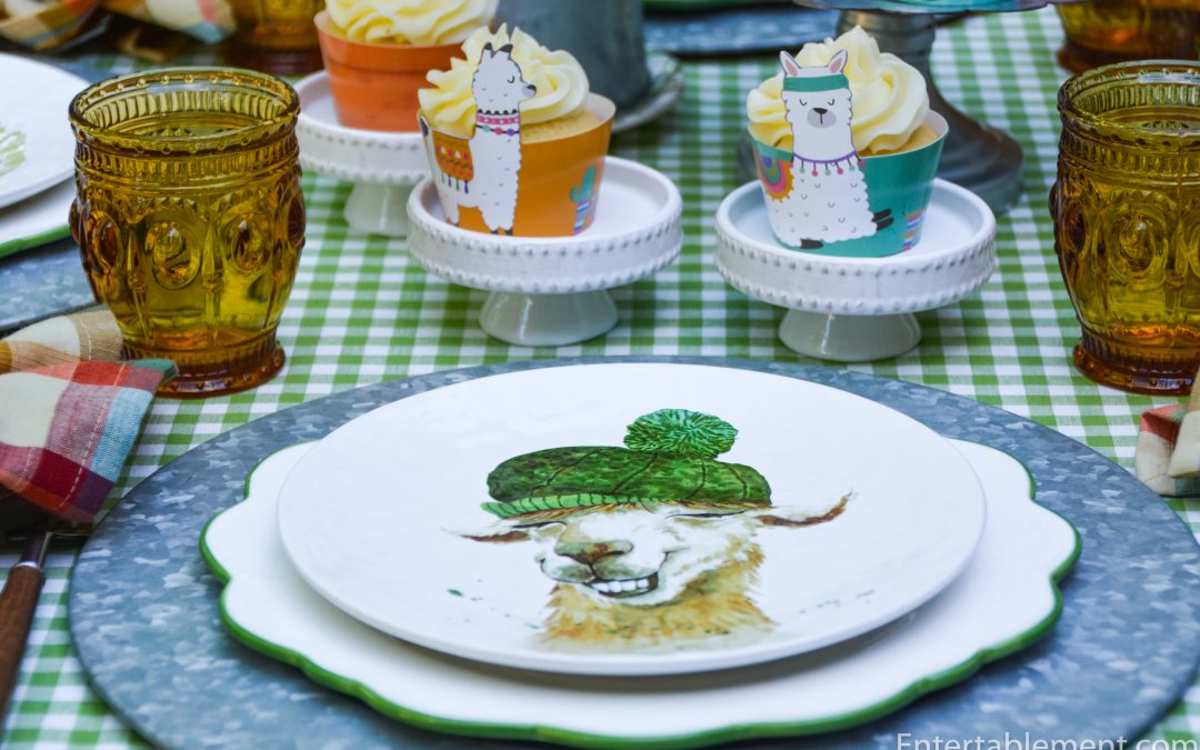 Pier 1 llama plate with a green knitted hat, galvanized charger, plaid napkin and frosted cupcakes.