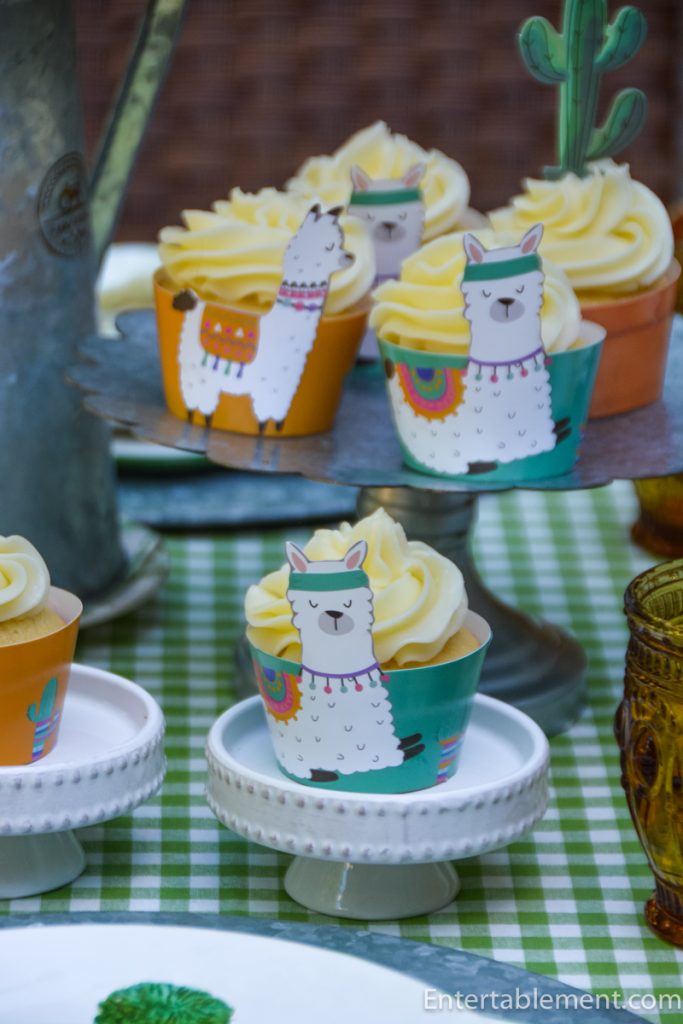 Vanilla cupcakes with raspberry filling and piped lime Swiss Meringue Buttercream in colourful llama cupcake wrappers.