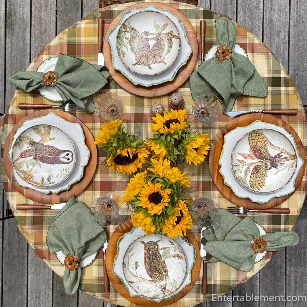 Rustic fall table set with owl-themed pasta bowls, plaid tablecloth, and sunflower centrepiece.