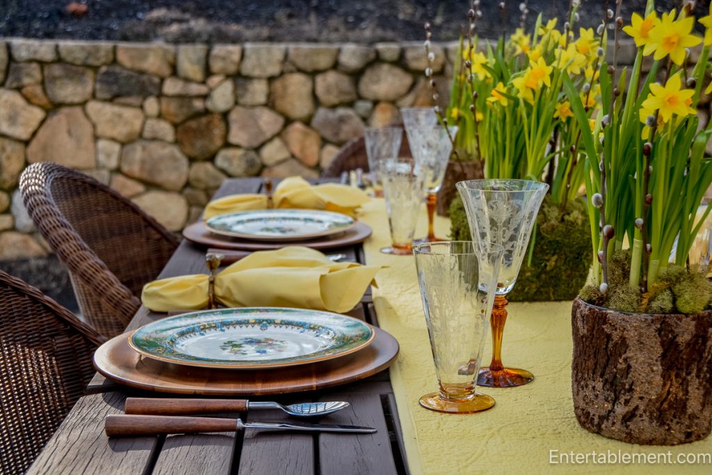 Spring outdoor tablescape with Garfield (Pareek) china, daffodil centerpieces, and amber glassware.