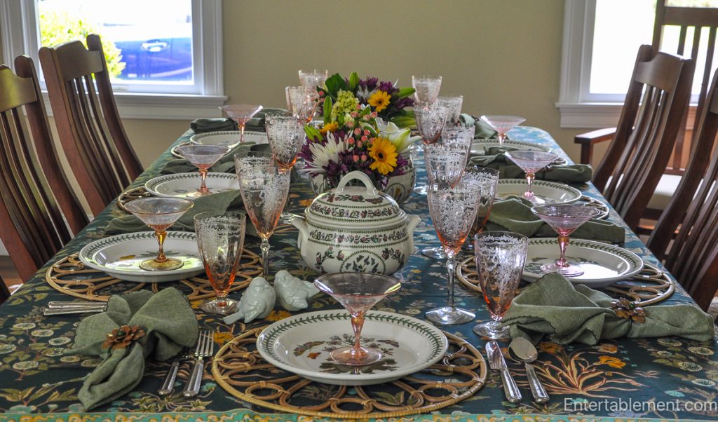 Elegant garden-themed table set with Portmeirion Botanic Garden china, pink Depression glass, and a floral centerpiece.