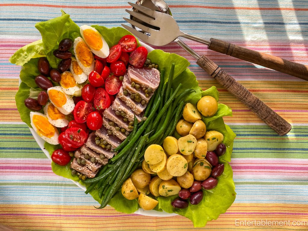 Overhead view of Salade Niçoise à la Julia arranged on a white platter with seared tuna, green beans, potatoes, eggs, and tomatoes.