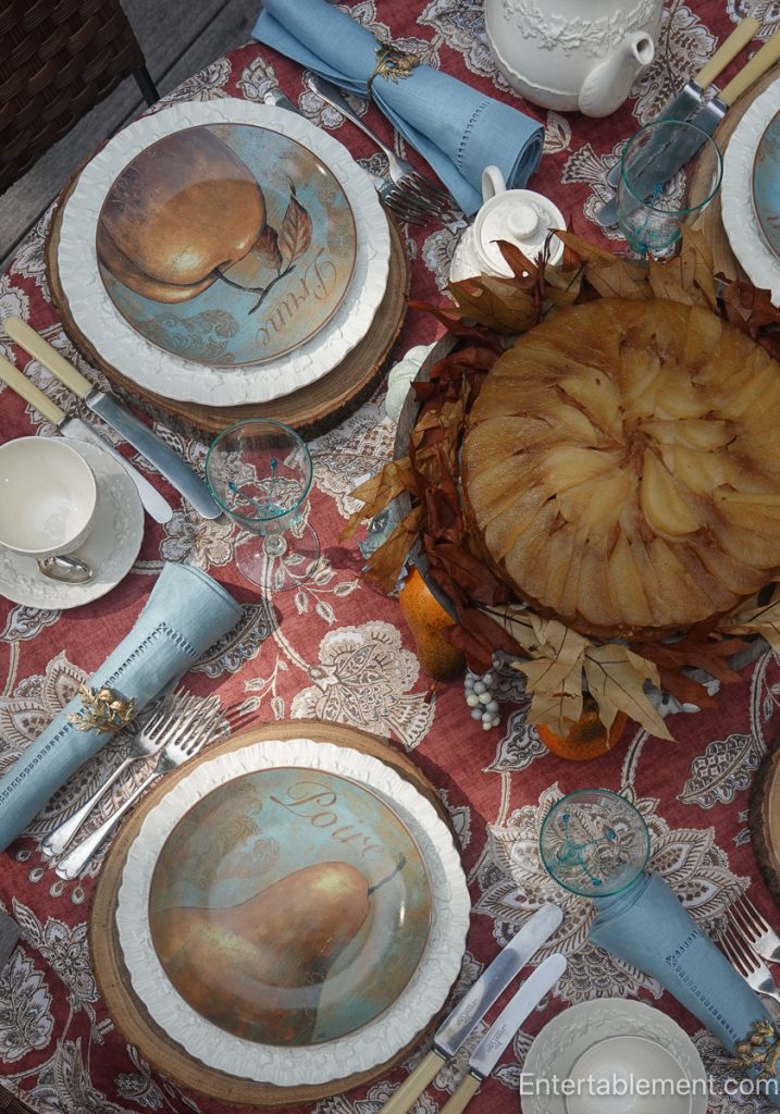Autumn tea table set with Pier 1 “Delicious” salad plates, Wedgwood cream-on-cream china, and a Pear-Maple Upside-Down Cake at the centre, surrounded by small pumpkins and hydrangeas.