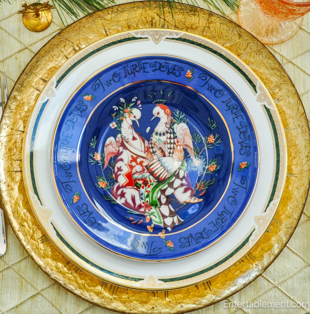 Anthropologie ‘Two Turtle Doves’ plate in blue with floral doves and decorative script, on gold charger.