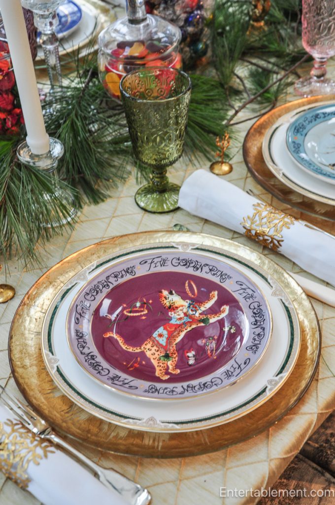 Cluster of candlesticks, pine branches, and candy jars adding height and texture to the Christmas table.