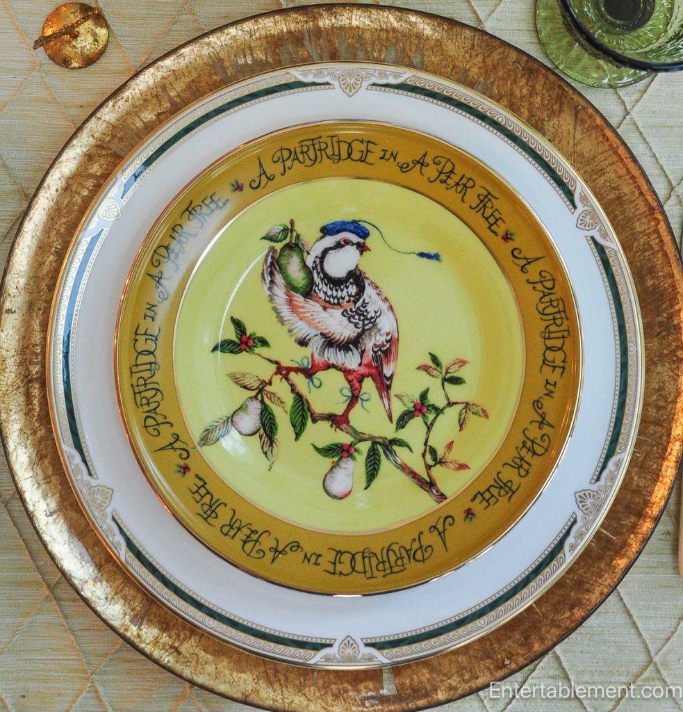 Anthropologie ‘Partridge in a Pear Tree’ plate in yellow with illustrated partridge and pear border, displayed on gold charger.