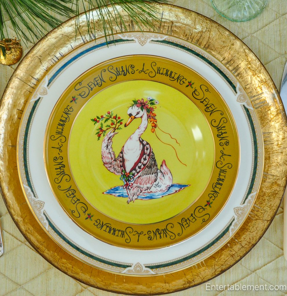 Anthropologie 'Seven Swans a-Swimming’ plate with majestic swan on bright yellow background, framed by hand-lettered script.