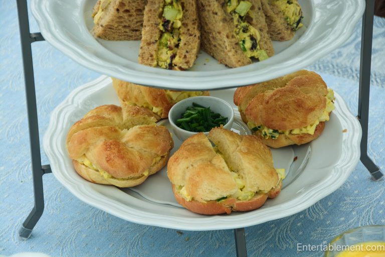 Traditional afternoon tea sandwiches including curried chicken and egg salad on tiered serving tray