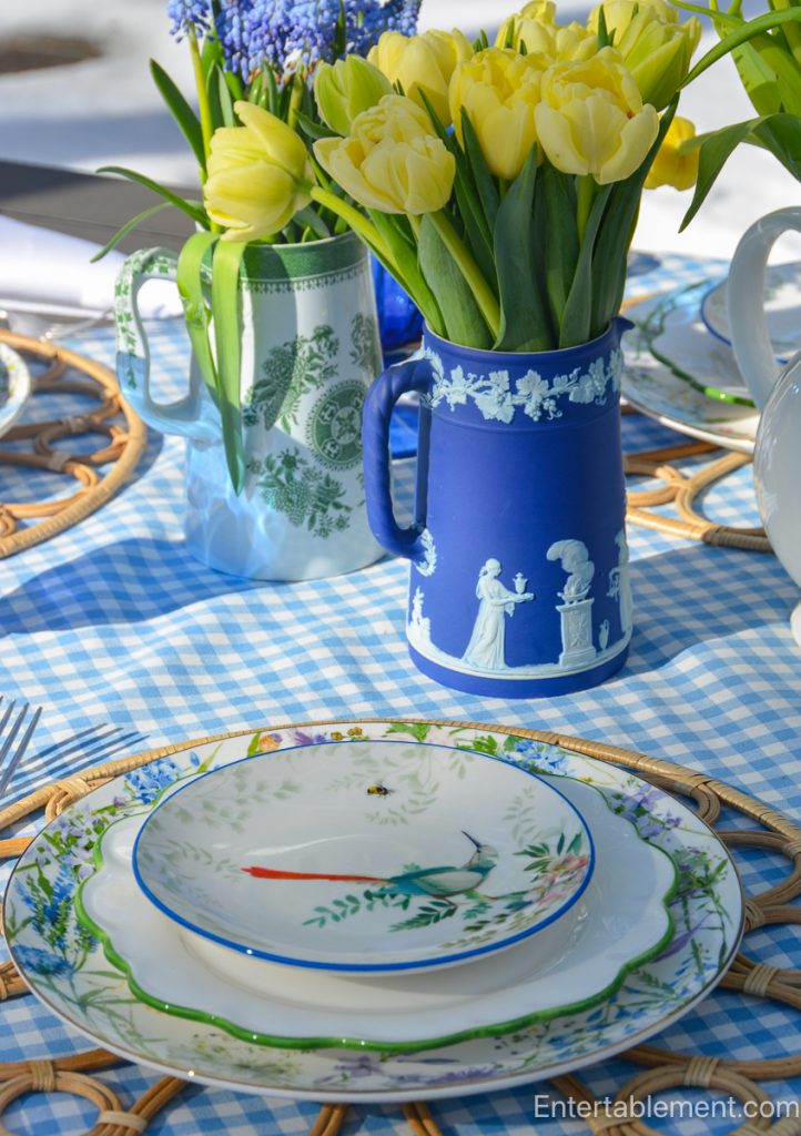 Close-up of spring flowers in blue and white pitchers used as a centerpiece on an outdoor table