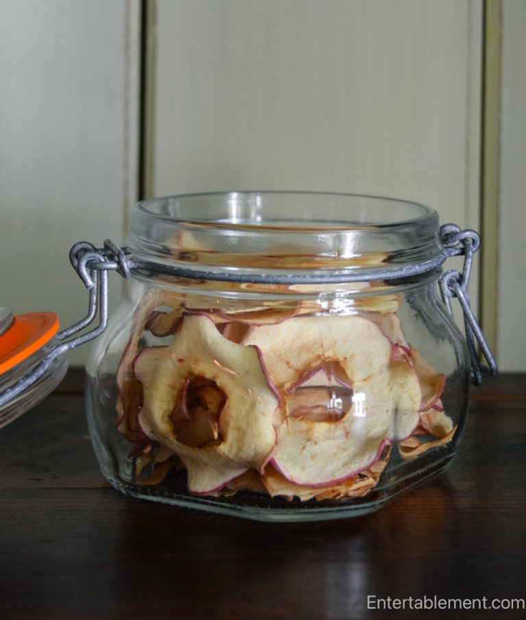 Glass flip-top jar filled with homemade apple chips, perfect for snacking or adding to autumn salads.