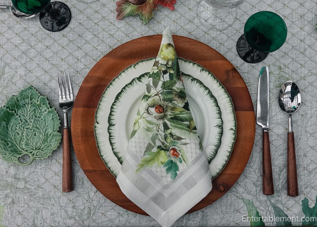 Williamsburg Green china layered with a Chestnut-patterned napkin, wooden charger and green leaf dish.