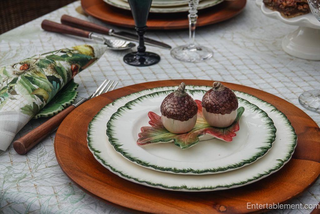 Wedgwood Williamsburg Green place setting with wooden charger, acorn salt and pepper shakers and green stemware.