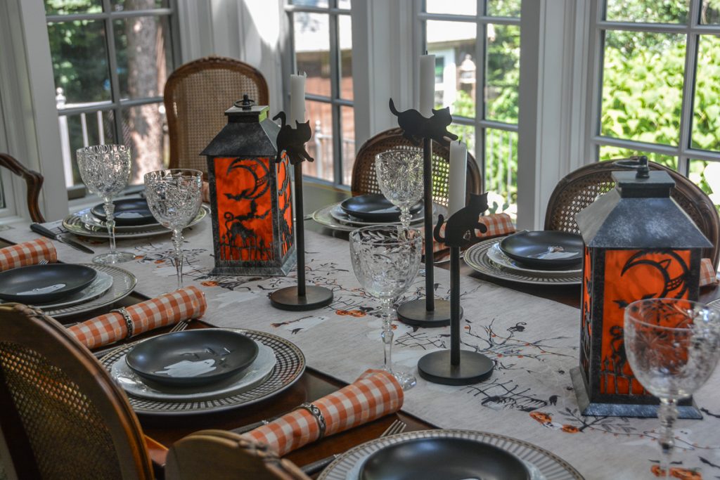 Halloween dining table with orange-panelled lanterns, clear stemware and ghost place settings